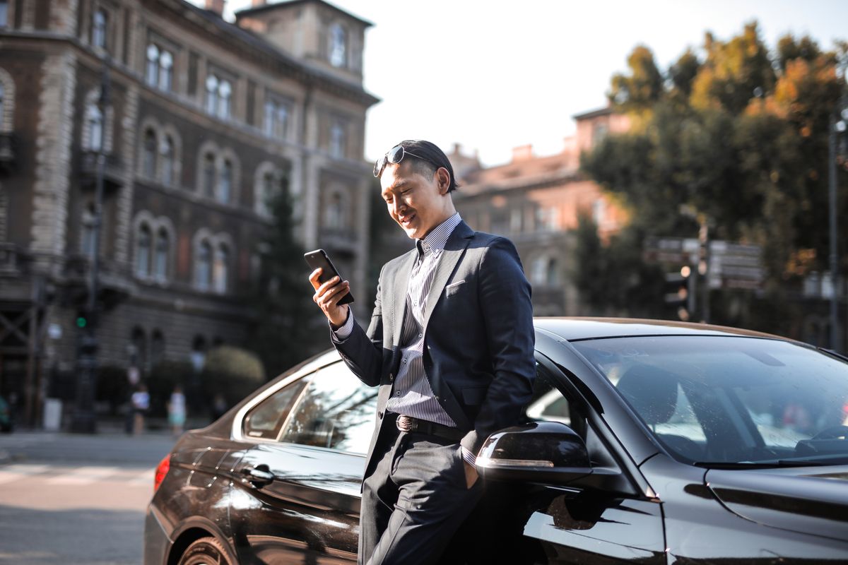Automobiliste consultant son smartphone à côté de sa voiture