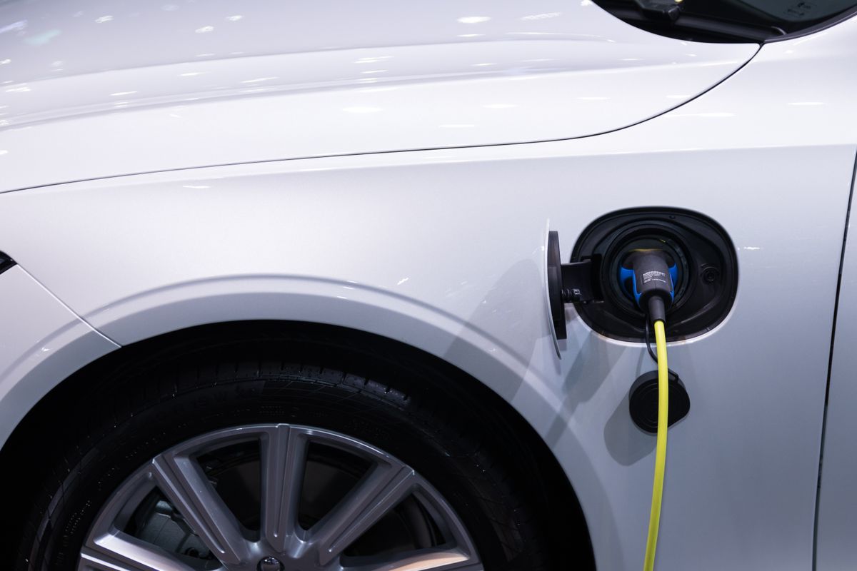 Voiture électrique blanche branchée sur une borne de recharge